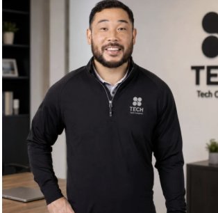 Man in a decorated black quarter-zip in an office
